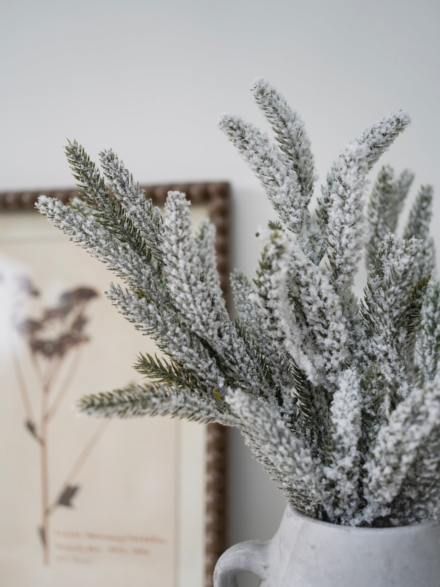 Frosted artificial plant in a white pot with a blurred background