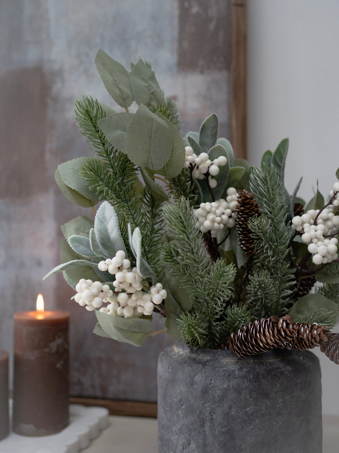 Faux christmas greenery arrangement with white berries in a concrete pot on a neutral background