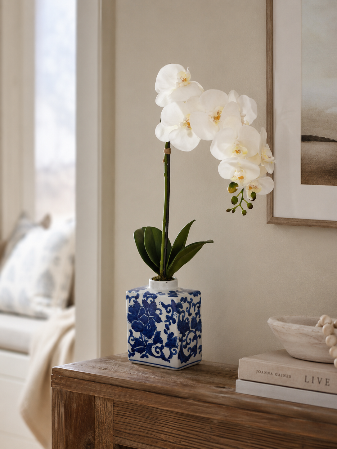 White orchid in a blue and white chinoiserie vase on a wooden table in a living room.