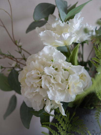 Bouquet of faux white flowers with green leaves on a neutral background