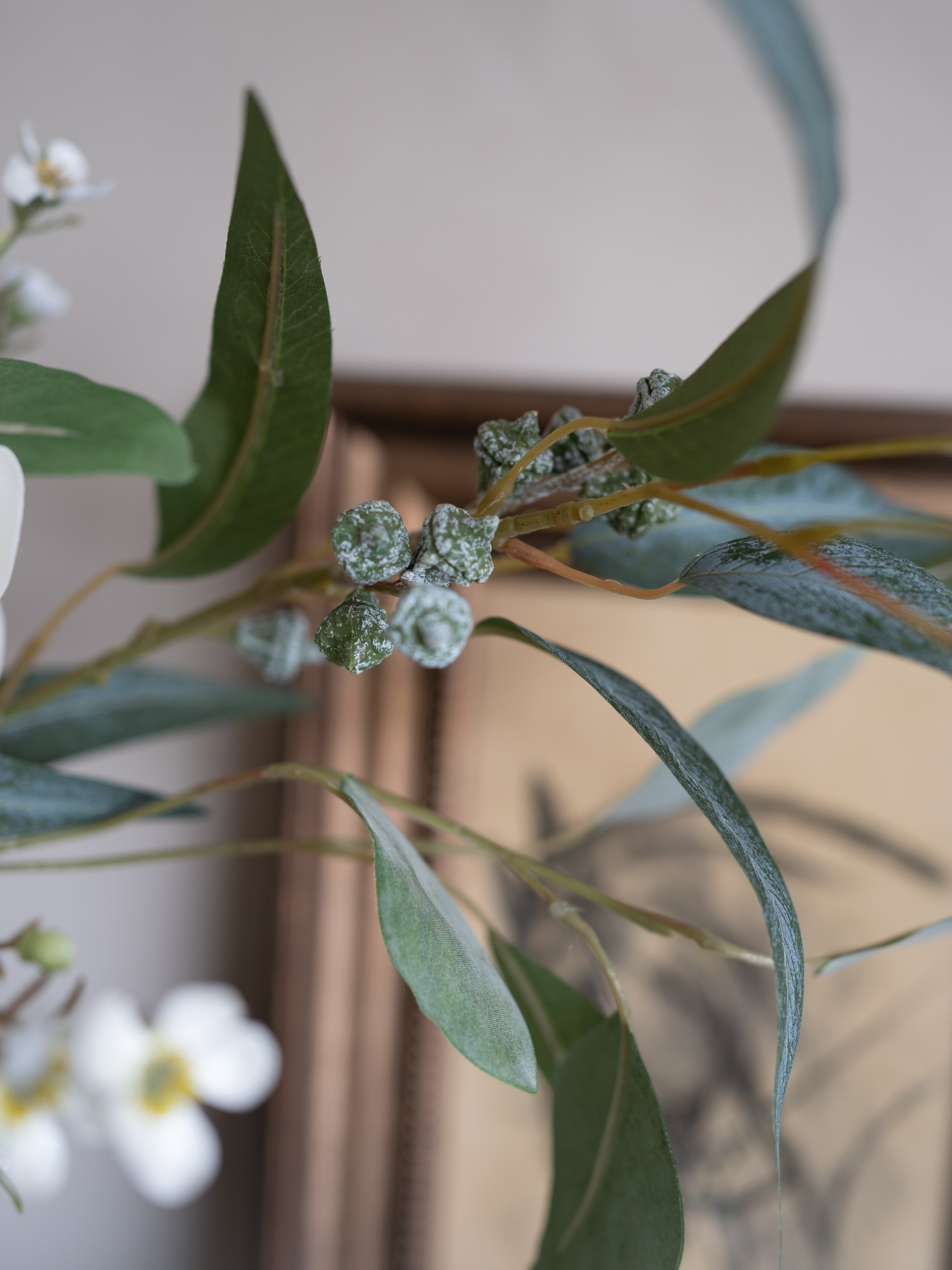 Close-up of faux green leaves and small white flowers with a blurred background
