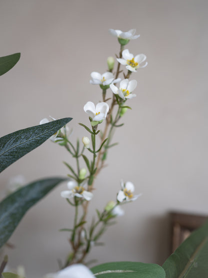 faux White flowers with green leaves against a neutral background