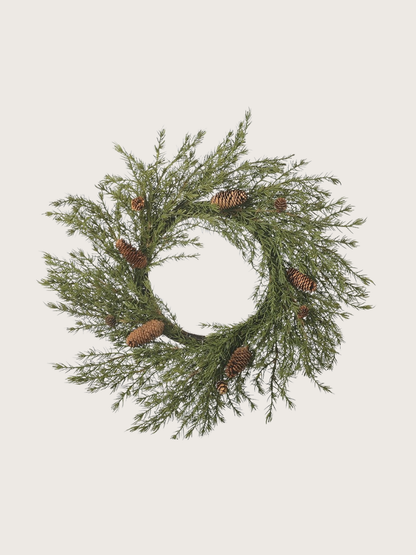faux christmas foliage wreath with pinecones on a light gray background