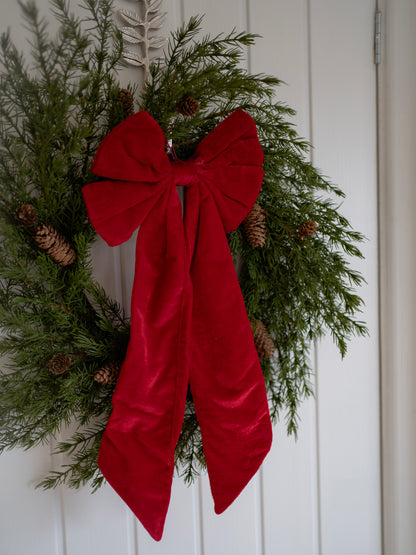 Christmas wreath with a large red bow on a white door