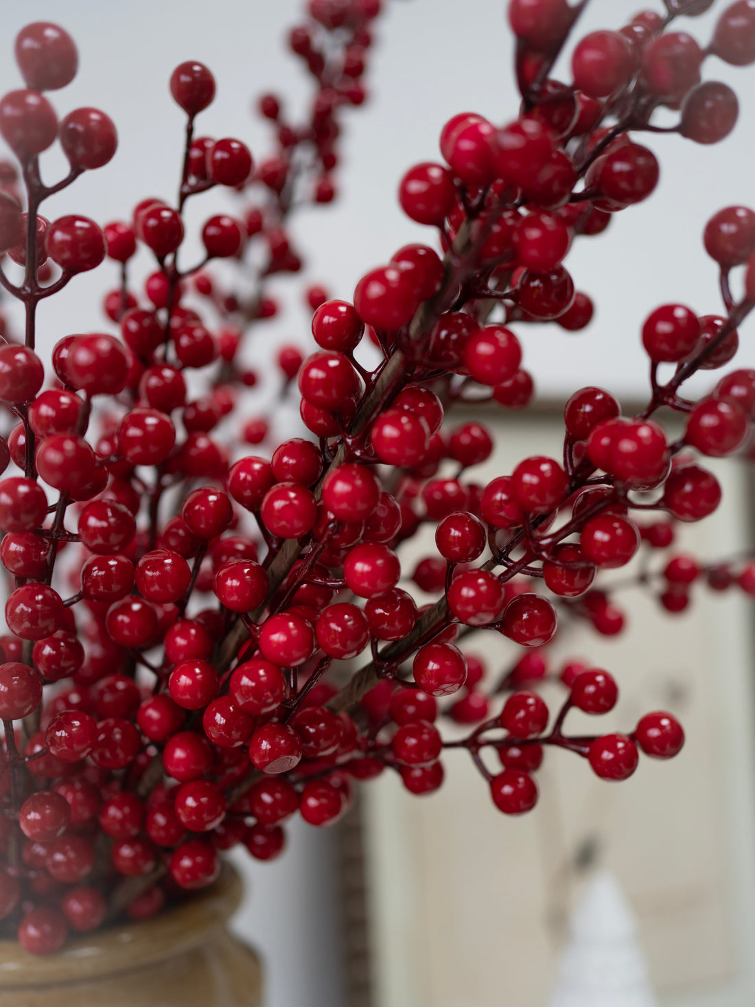 Close-up of faux red berries on a branch with a blurred background