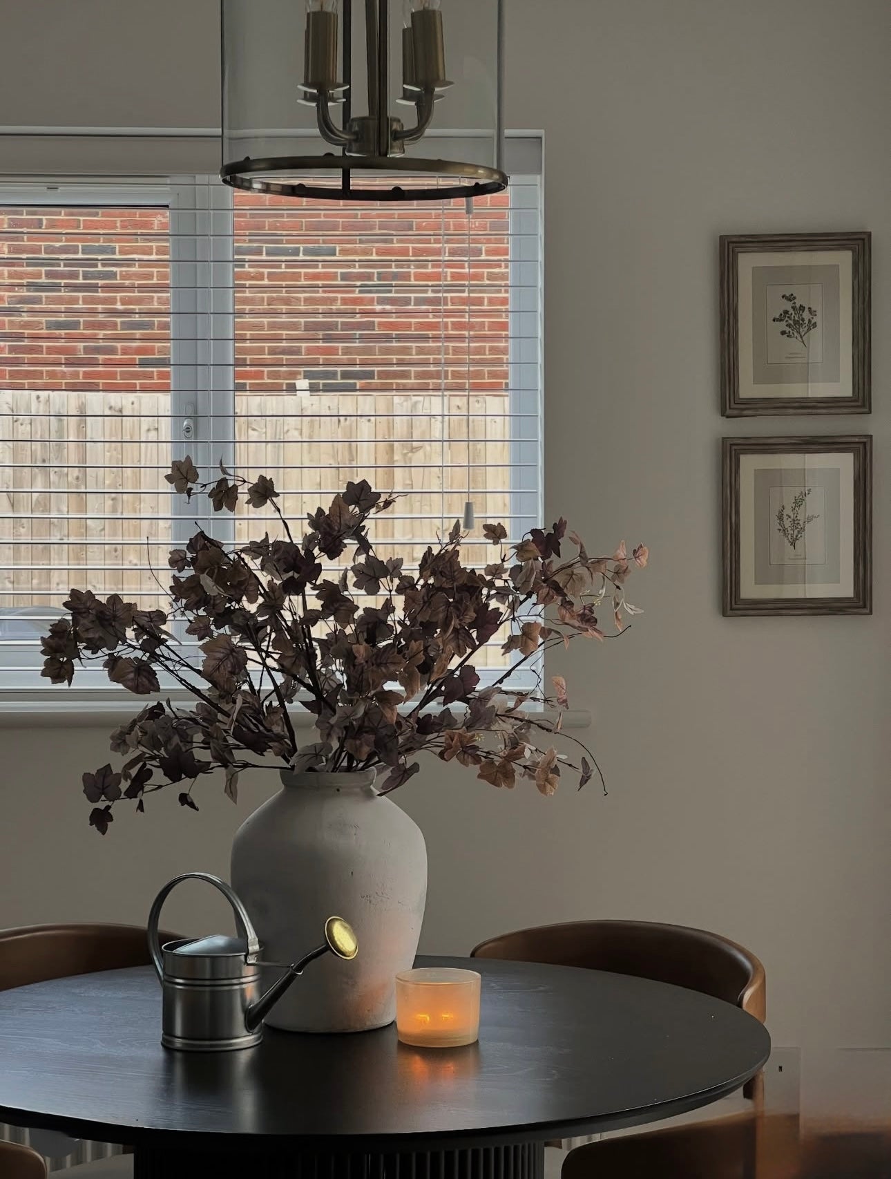 Dining room with a vase of dried flowers on a table, candle, and decorative items.