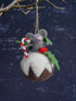 Felted Christmas ornament of a mouse in a pudding with candy cane and holly on a dark snowy background.