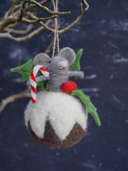 Felted Christmas ornament of a mouse on a pudding with candy cane and holly leaves against a dark background.
