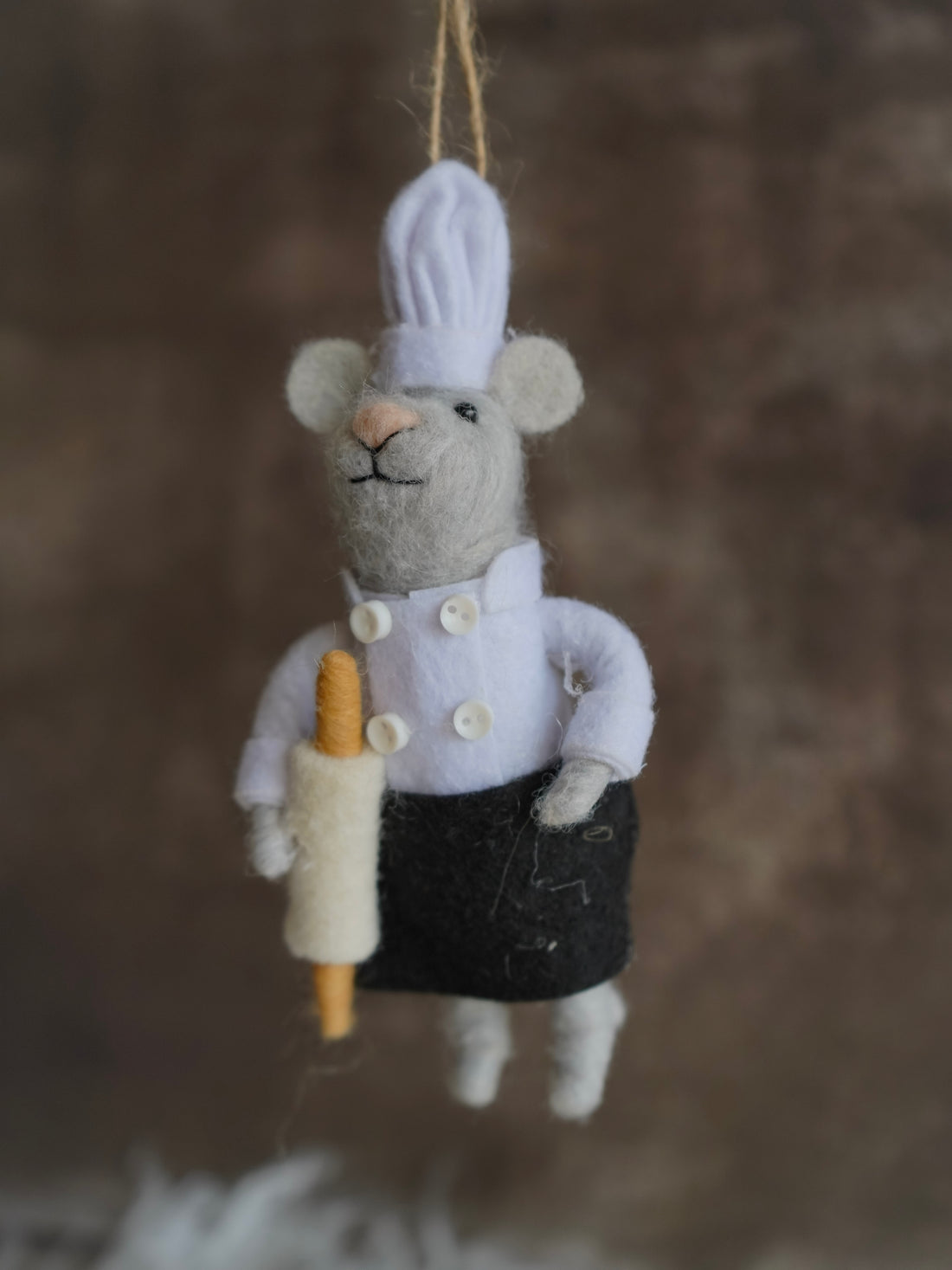 Felt mouse ornament dressed as a chef with a rolling pin on a brown background