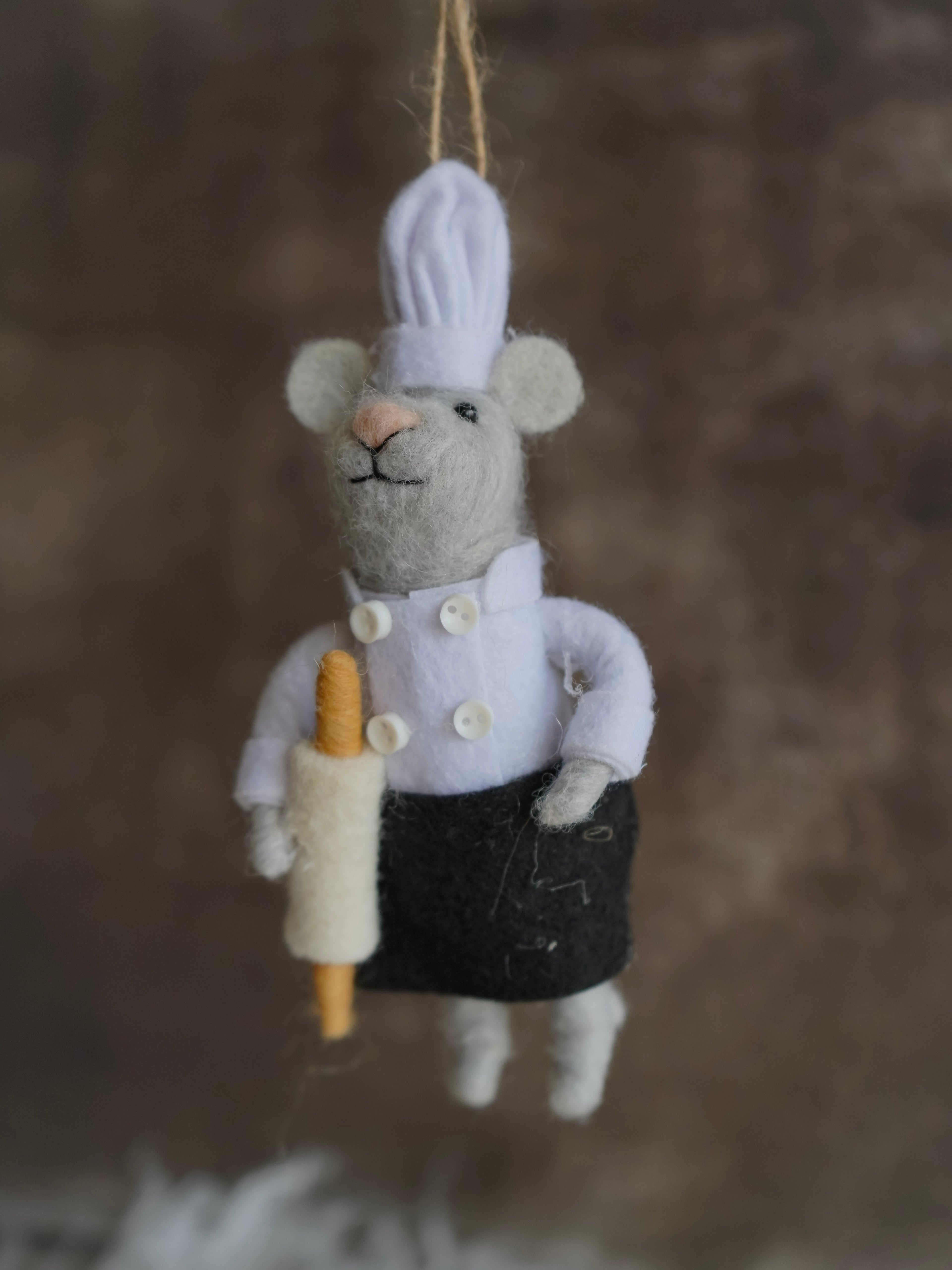 Felt mouse ornament dressed as a chef with a rolling pin on a brown background