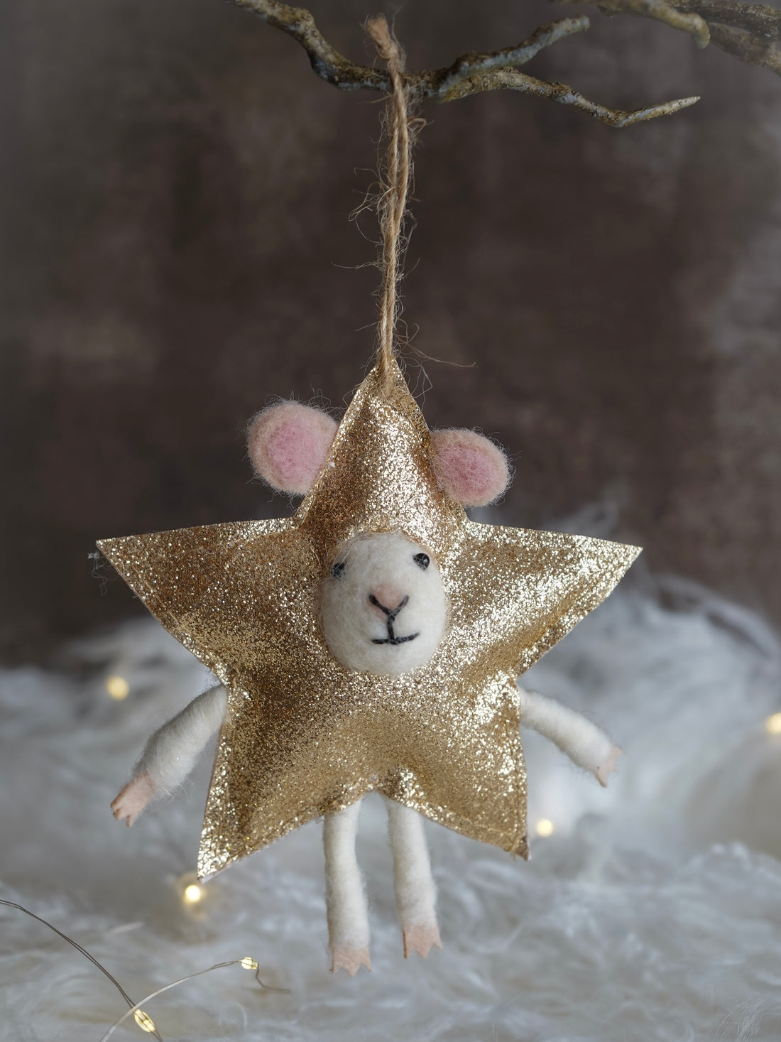 Decorative ornament with a star-shaped gold glitter body and a white face on a soft, blurred background.