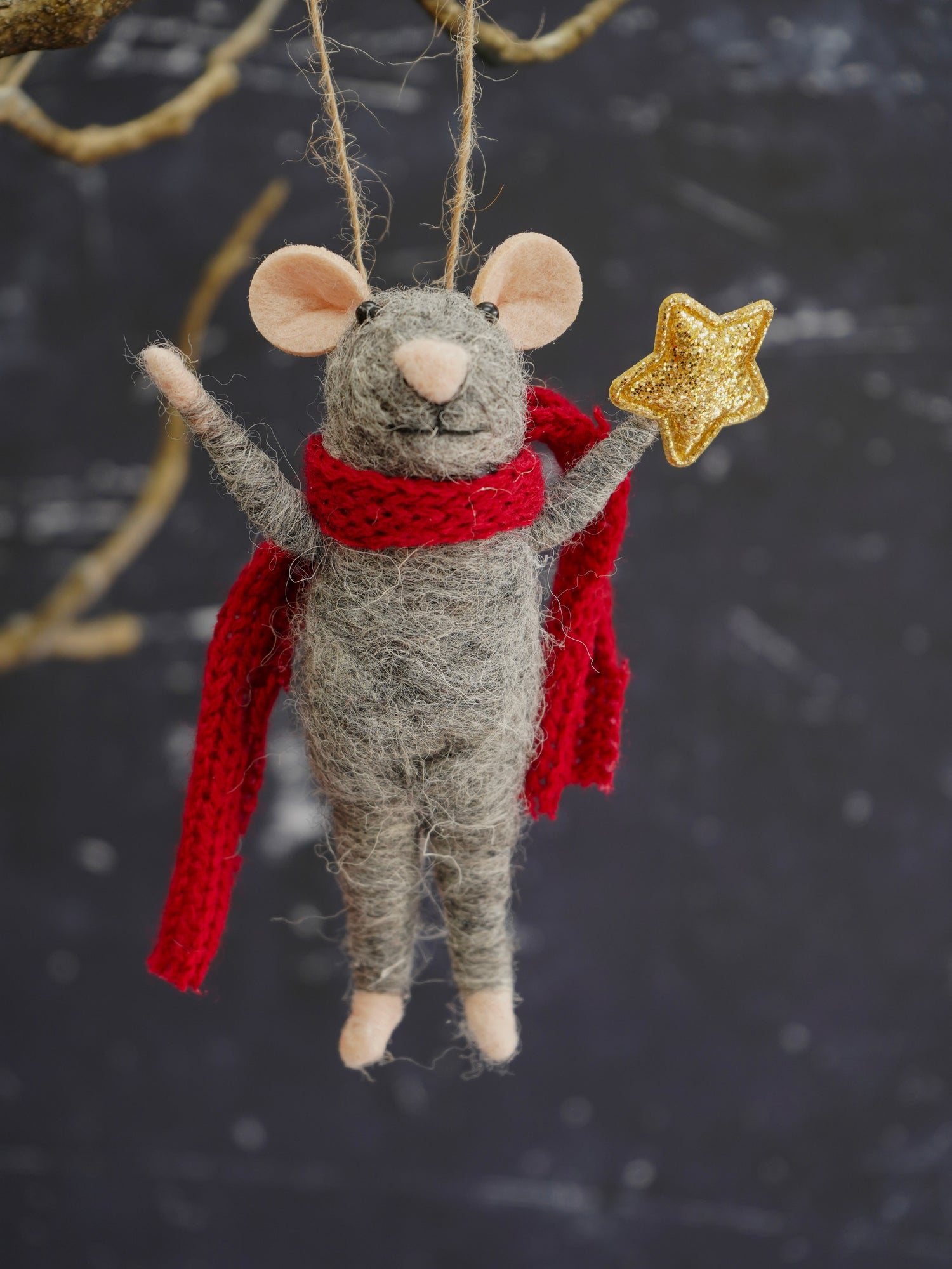 Decorative mouse ornament with a red scarf and gold star against a dark background