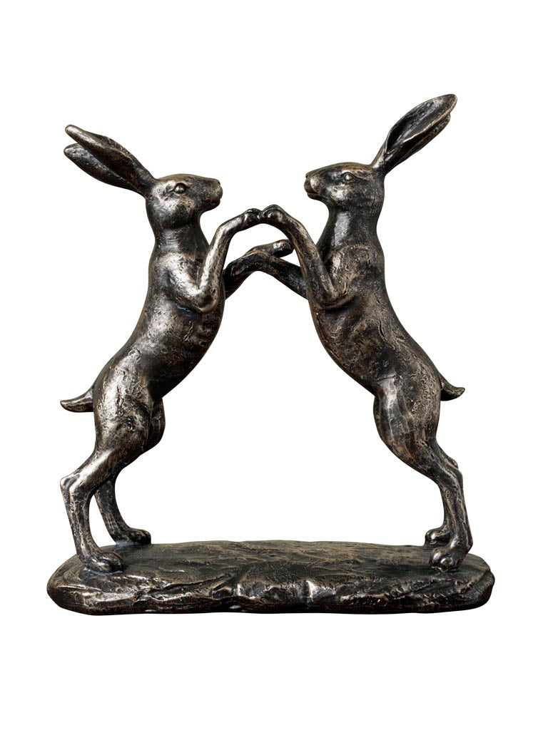 Bronze sculpture of two hares boxing on a white background