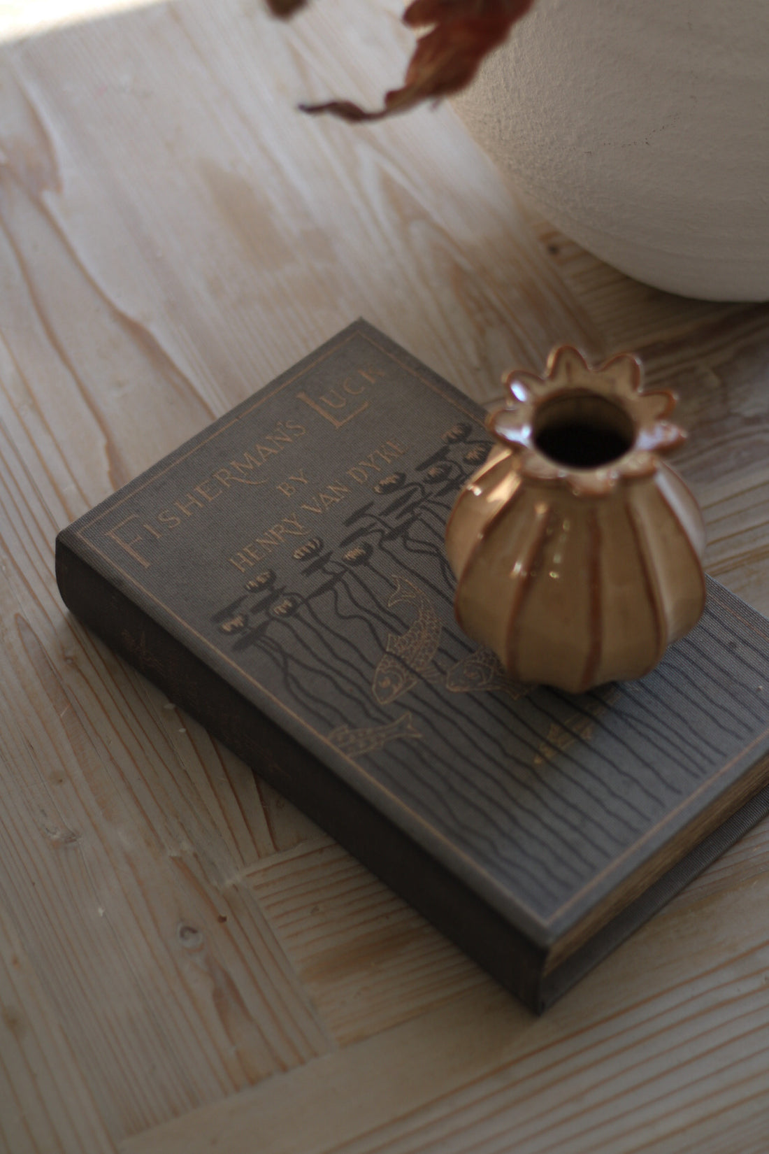 Small gold vase on an open book with a wooden surface background