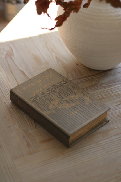 Vintage book on a wooden surface with a vase in the background