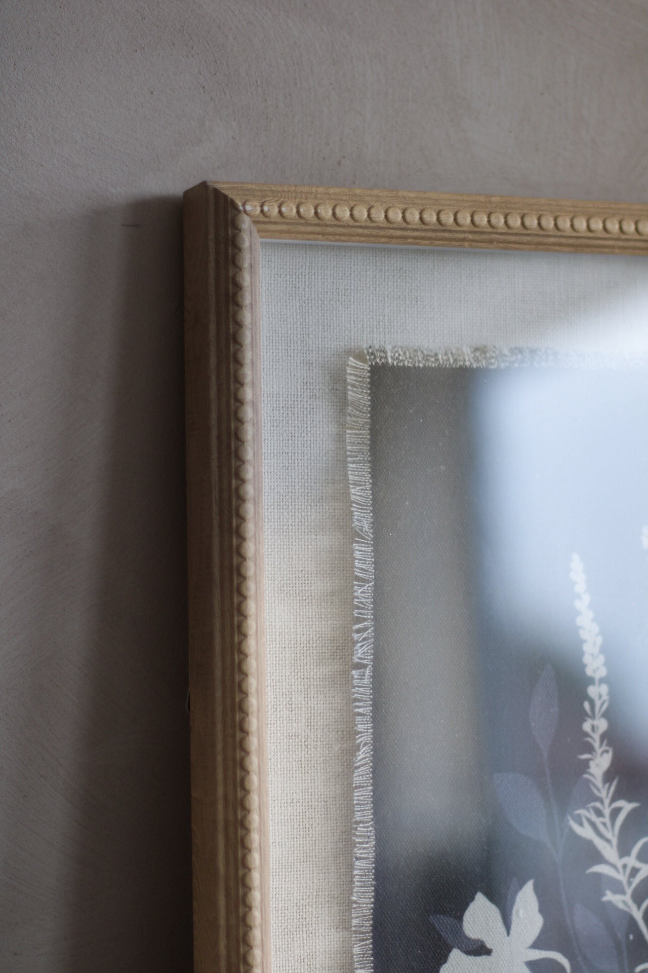 Beaded-framed mirror with floral design on a gray wall