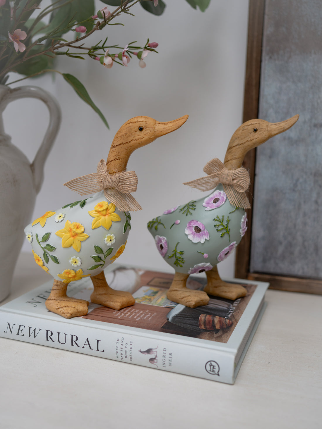 Two decorative duck figurines with floral patterns on a book
