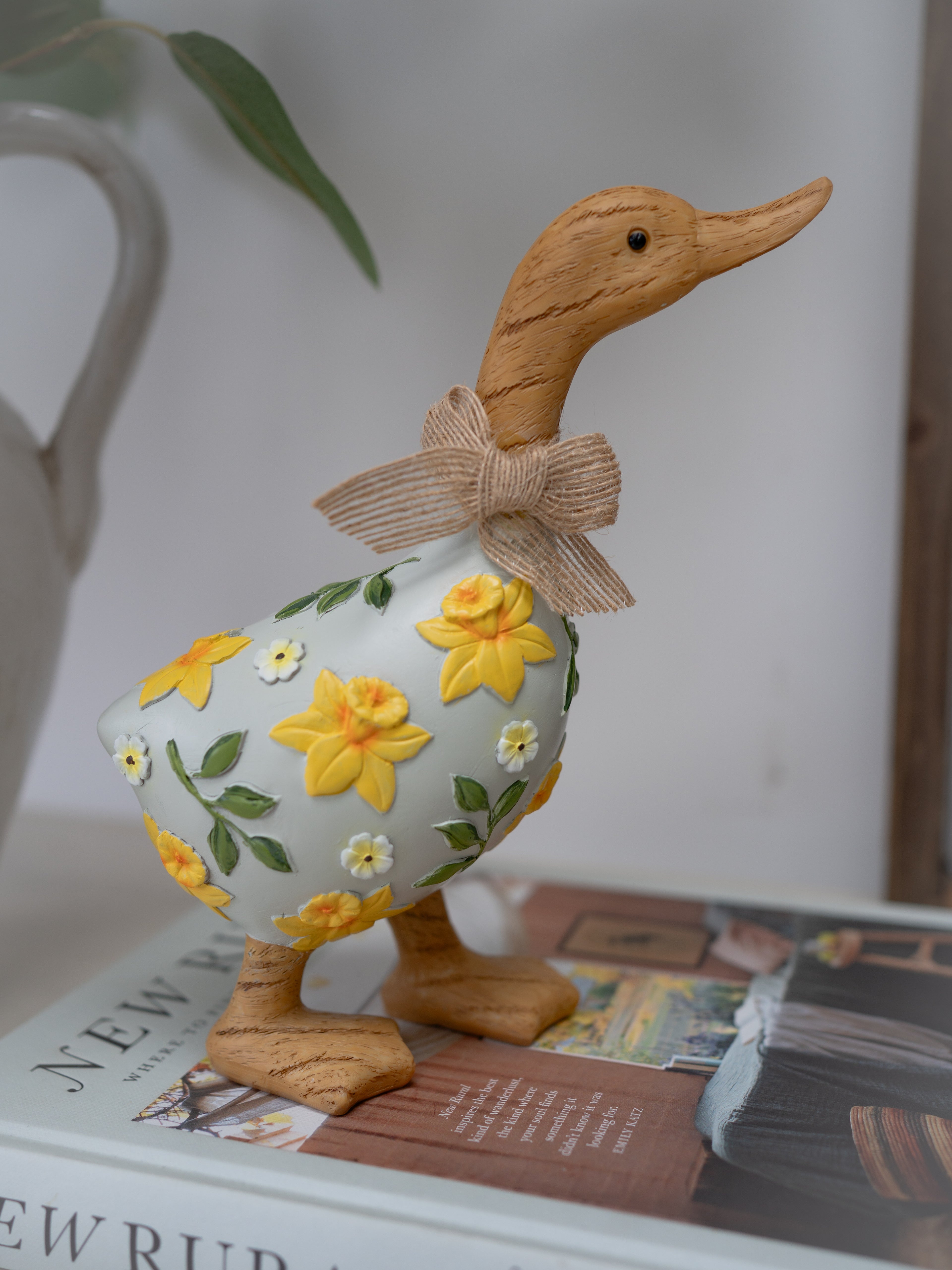 Decorative duck figurine with floral design and bow on a surface.