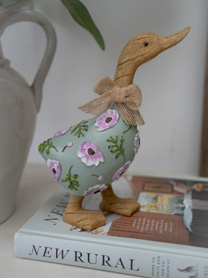 Decorative duck figurine with floral pattern and bow on a book
