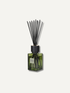 A reed diffuser bottle with a translucent olive green glass body, a black cap, and black reeds, shown against a light off-white background.