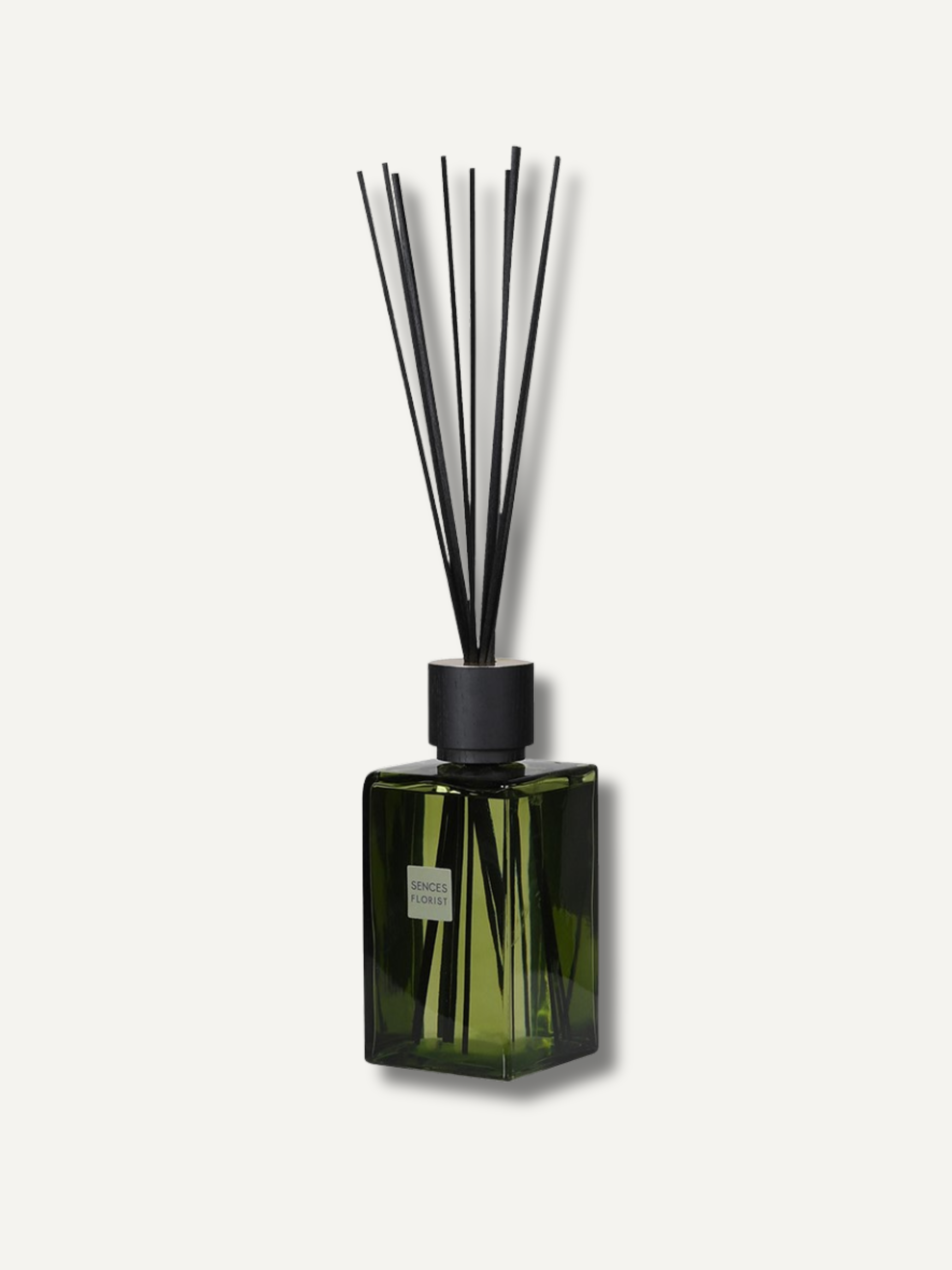 A statement reed diffuser with a dark green faceted glass bottle and black reeds, shown against a light off-white background.