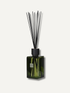 A statement reed diffuser with a dark green faceted glass bottle and black reeds, shown against a light off-white background.