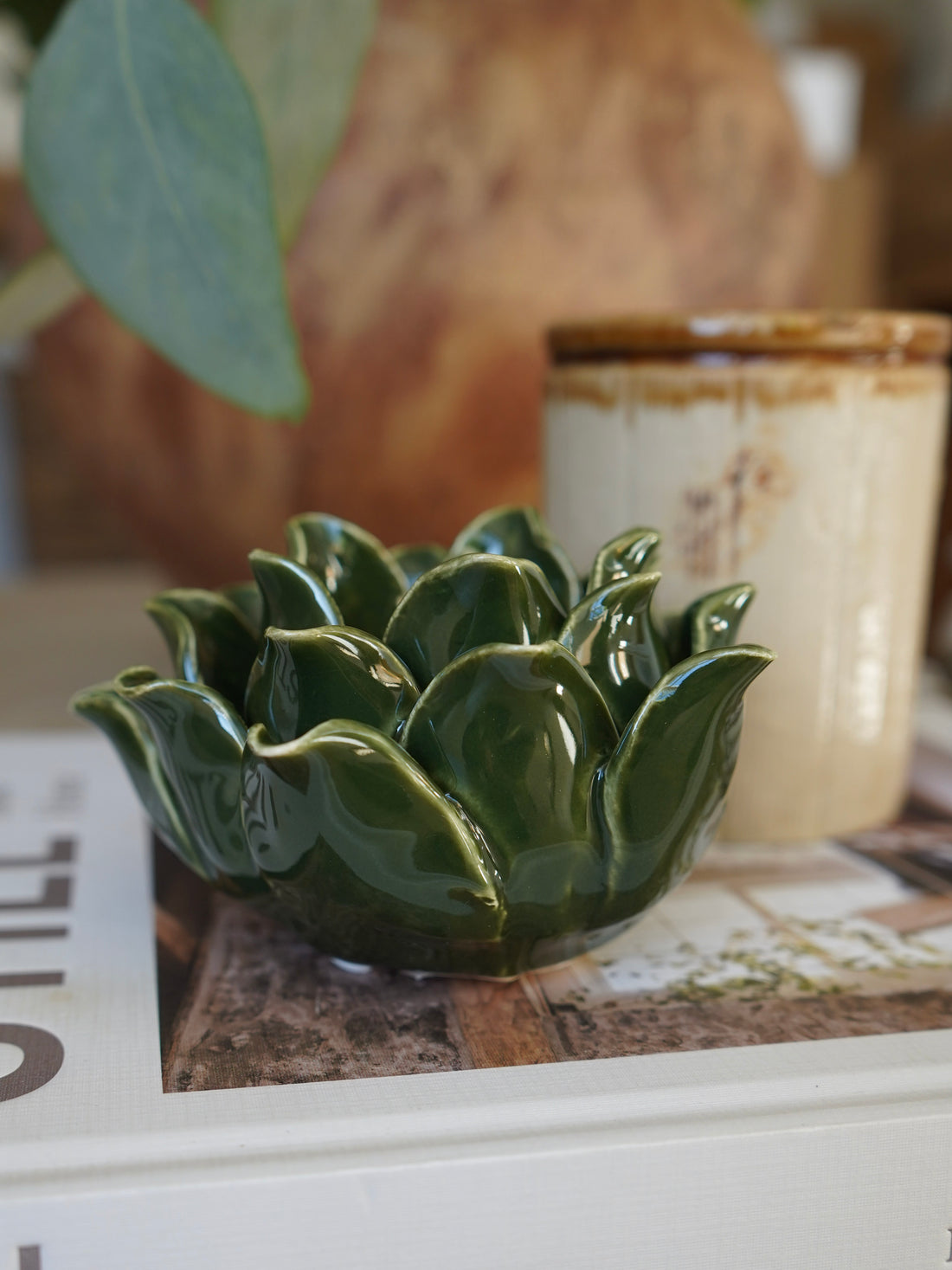 Green ceramic artichoke-shaped bowl on a surface with a blurred background