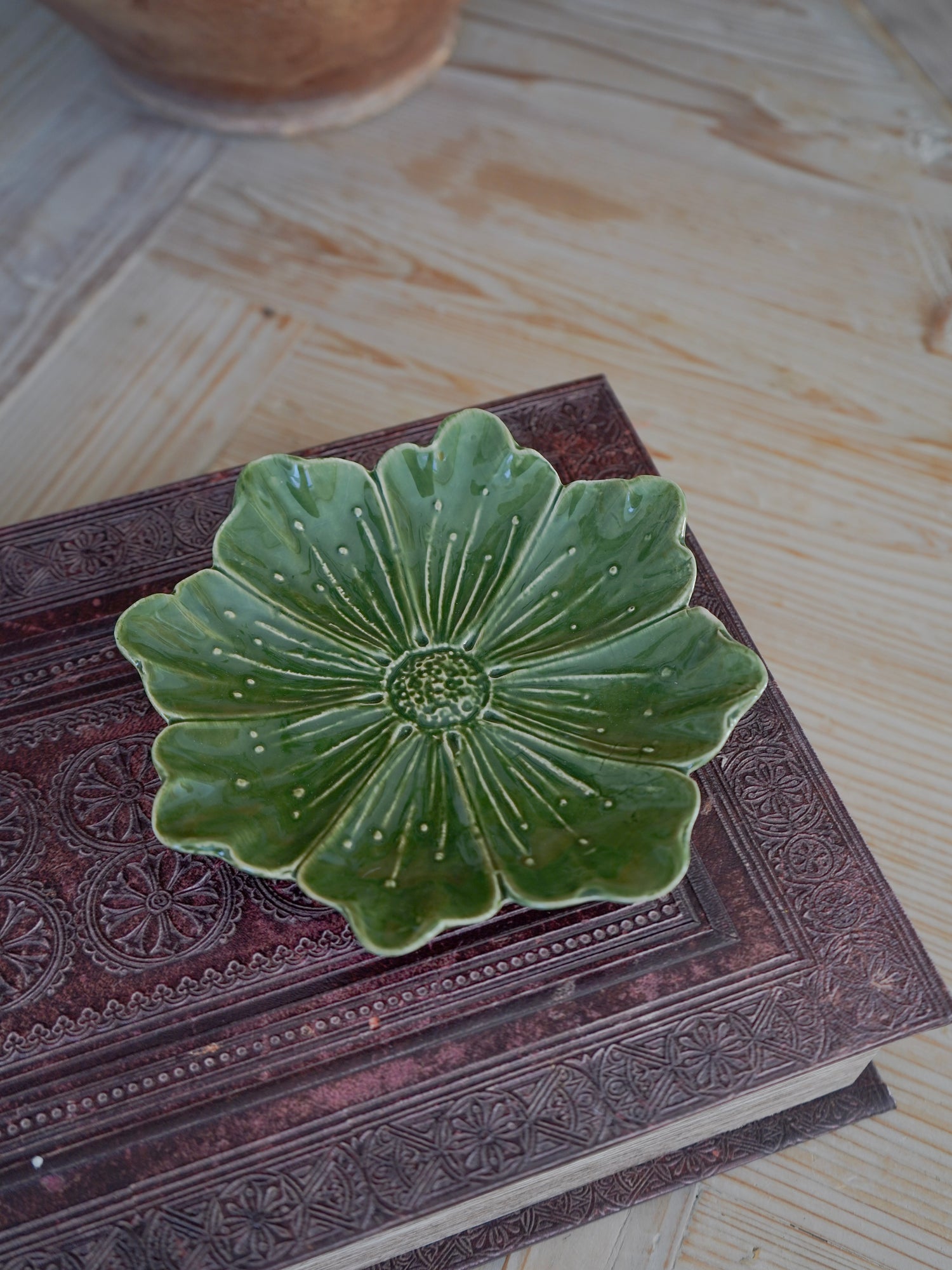 Green ceramic dish with floral design on a textured surface