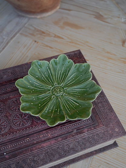 Green ceramic dish with floral design on a textured surface