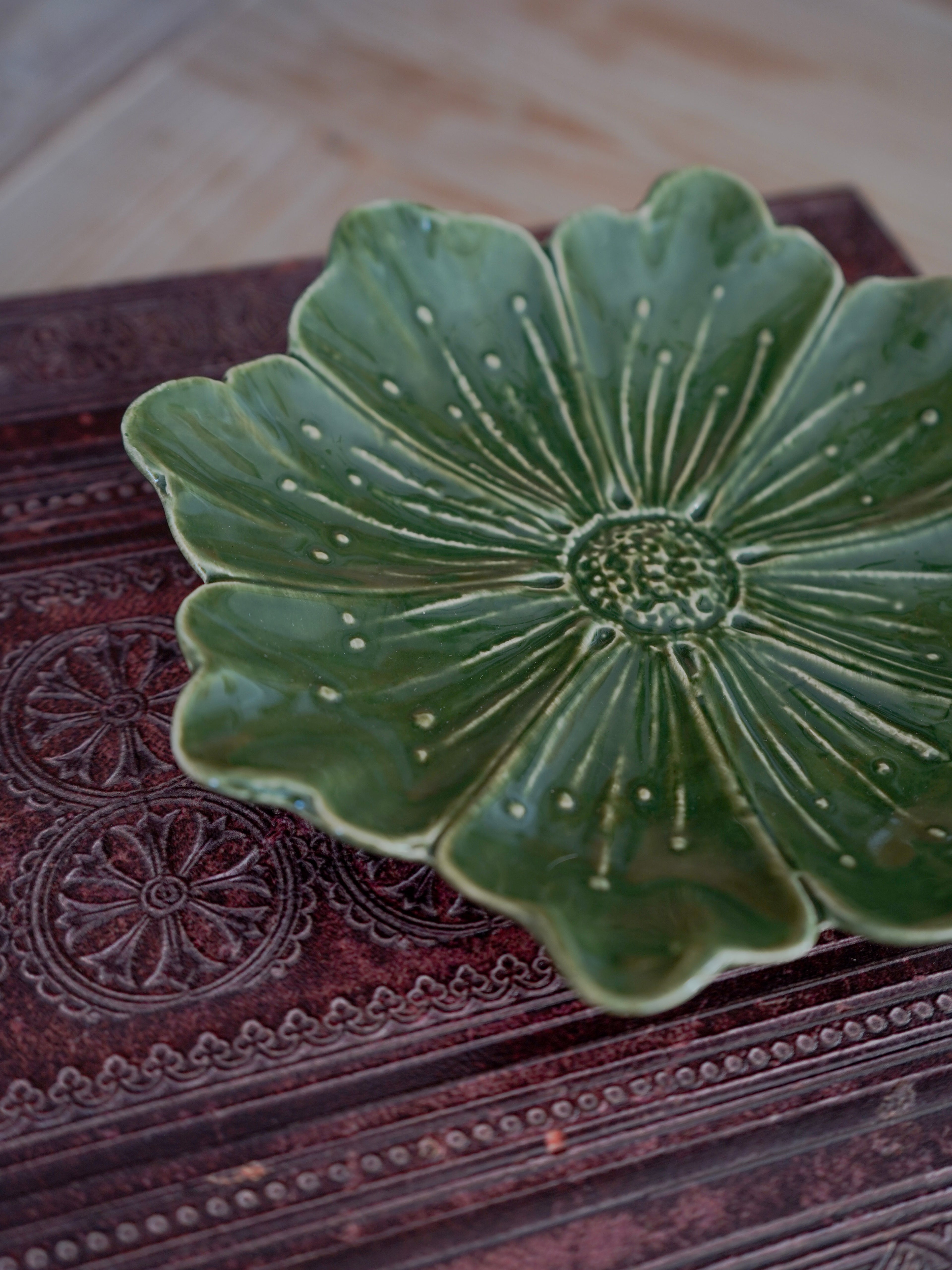 Green ceramic dish with floral design on a textured surface