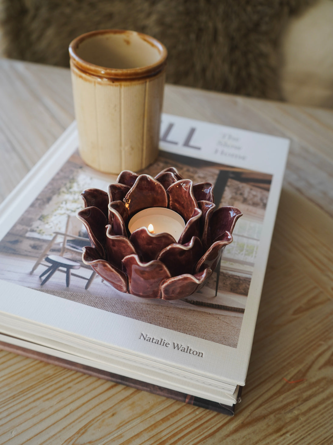 Ceramic flower-shaped candle holder with a lit candle on an open book