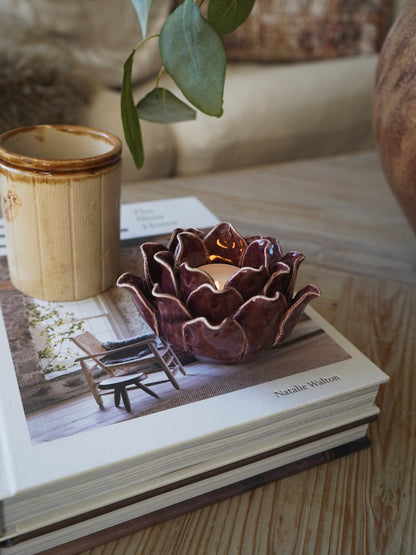 Ceramic flower-shaped candle holder on a book with a wooden surface background