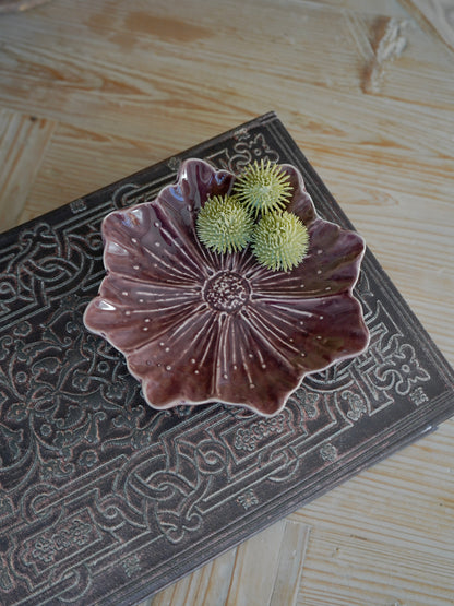 Decorative plum ceramic dish with floral design on a textured surface