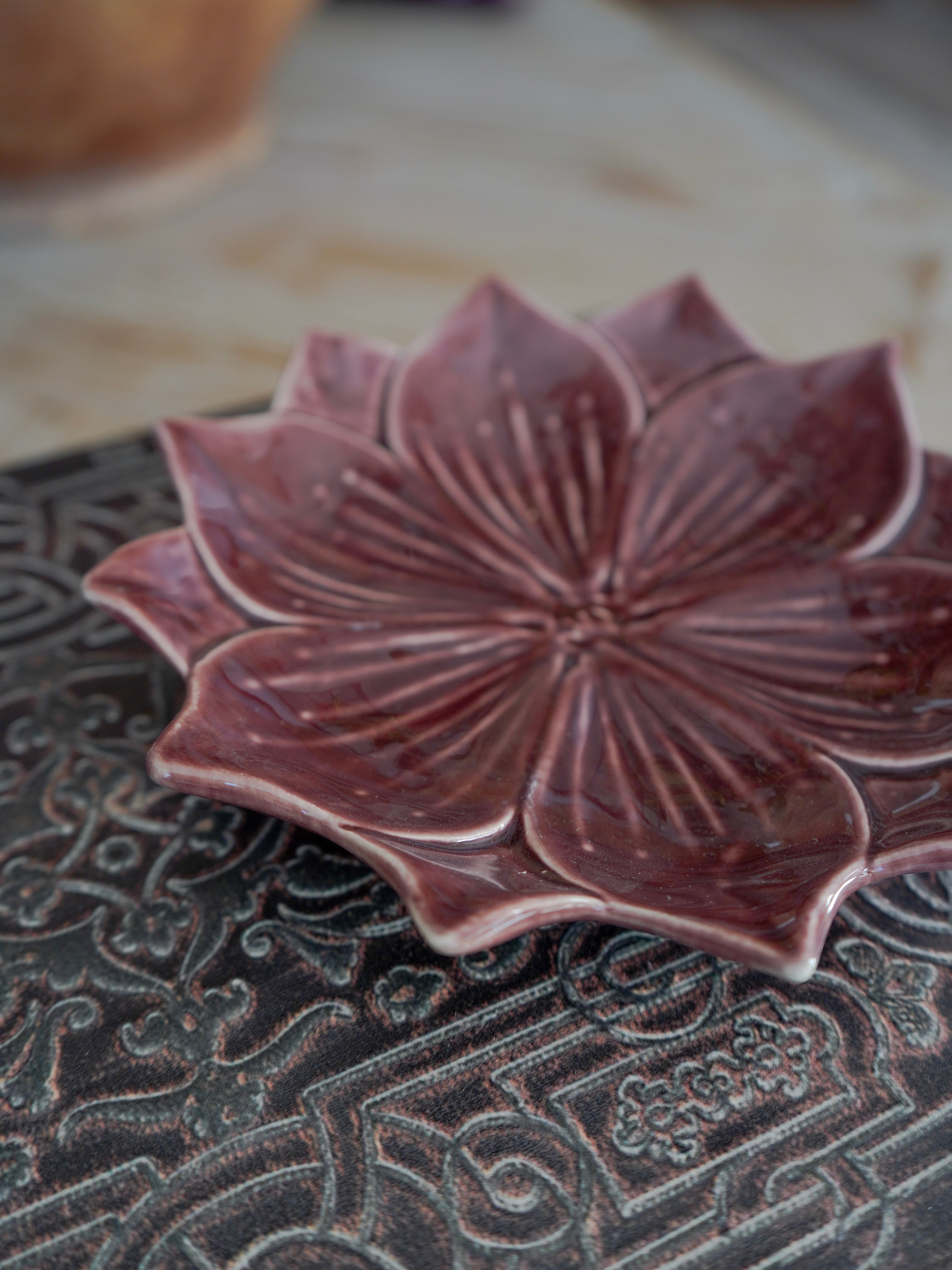 Ceramic flower-shaped dish on a textured surface