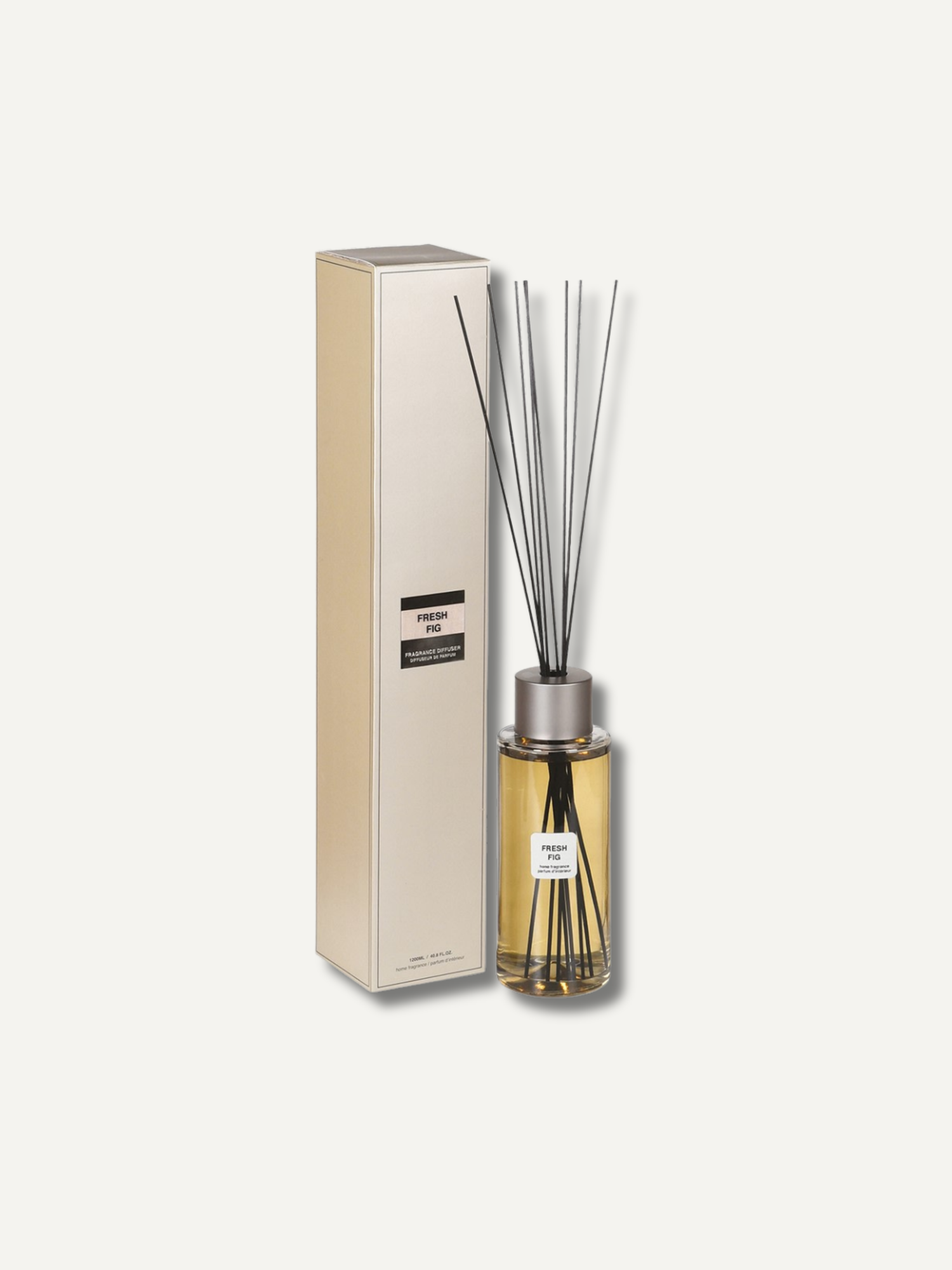 A statement reed diffuser bottle with amber liquid and reeds next to its tall cream-colored packaging box, set against a solid off-white background.