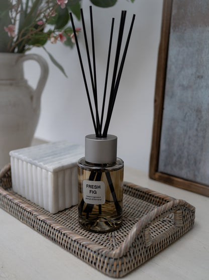 Diffuser with black sticks on a tray in a home setting