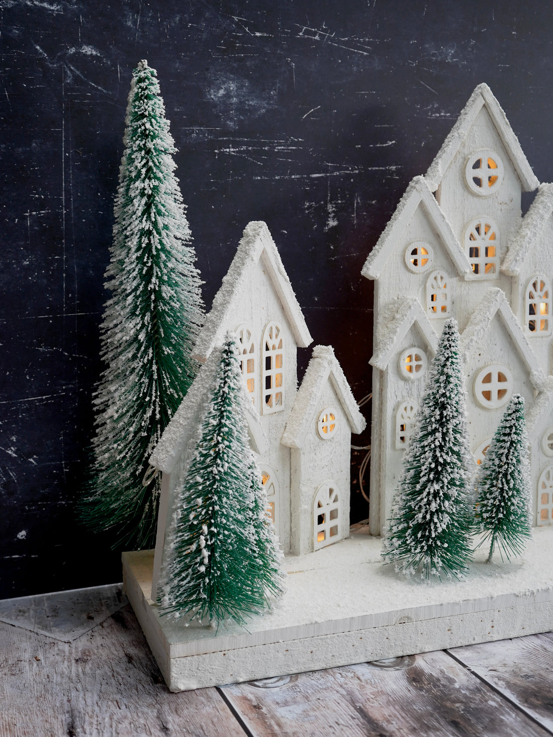 Decorative Christmas scene with white houses and trees on a dark background