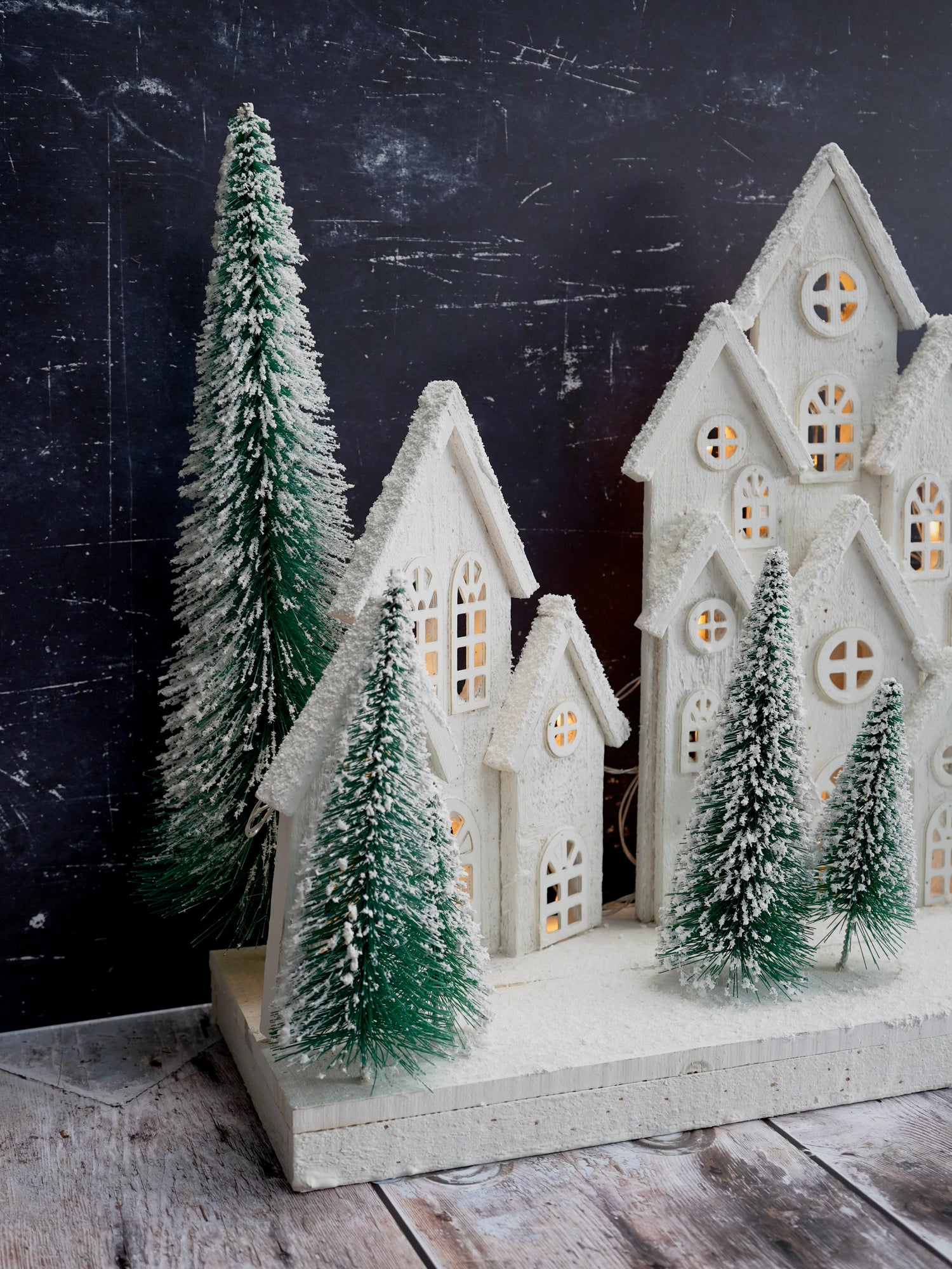 Decorative Christmas scene with white houses and trees on a dark background