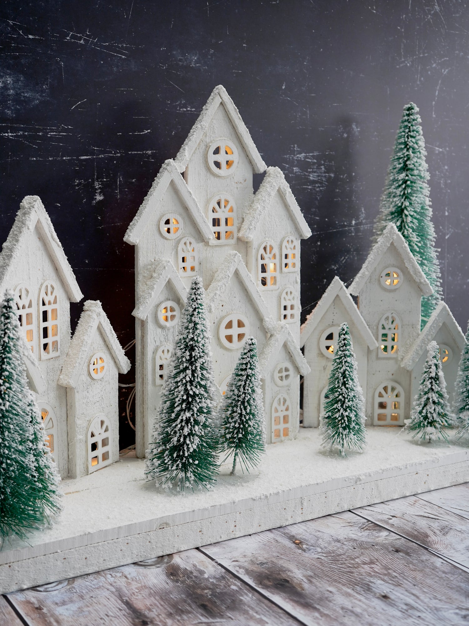 Decorative winter scene with miniature houses and trees on a dark background