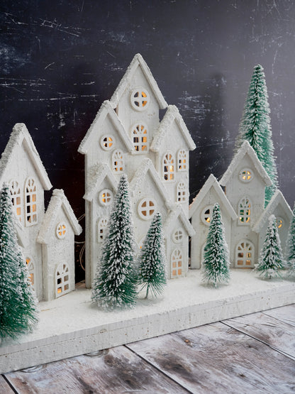 Decorative winter scene with miniature houses and trees on a dark background