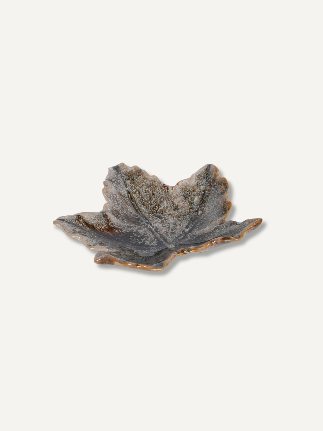 A small leaf-shaped ceramic dish with a textured, speckled glaze in earthy gray, brown, and beige tones, set against a solid off-white background.