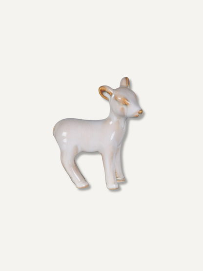 A small ceramic animal figurine shaped like a standing deer, shown on a plain light background.