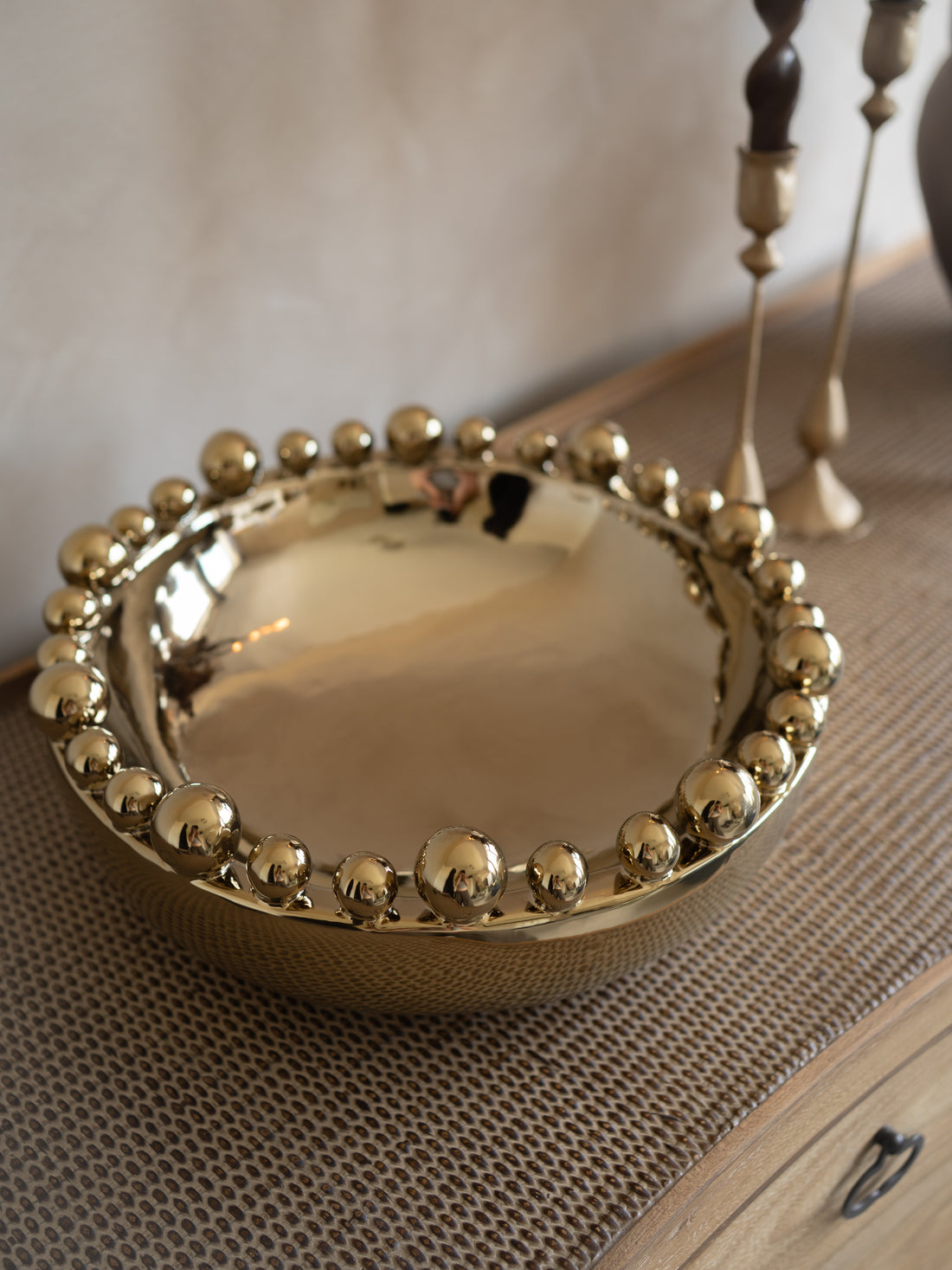 Gold decorative bowl with beaded edge on a textured surface