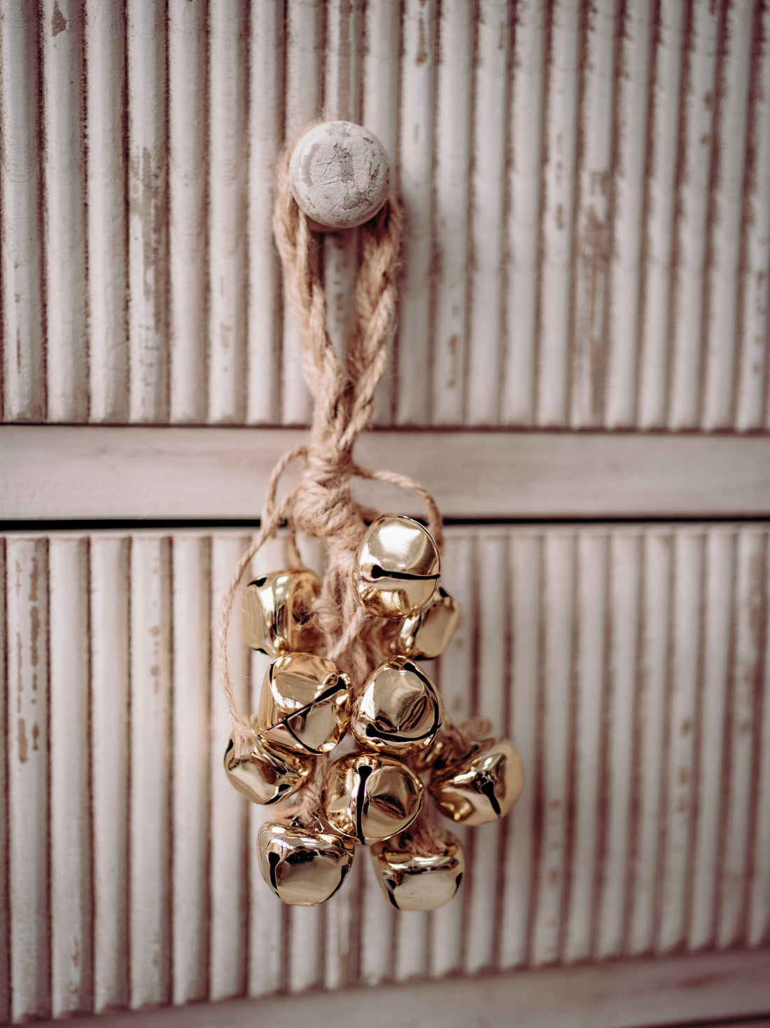 Gold jingle bells hanging on a wooden surface