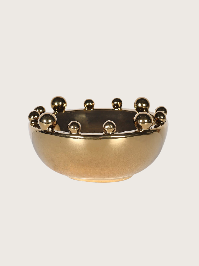 Gold decorative bowl with bobble embellishments on a light gray background
