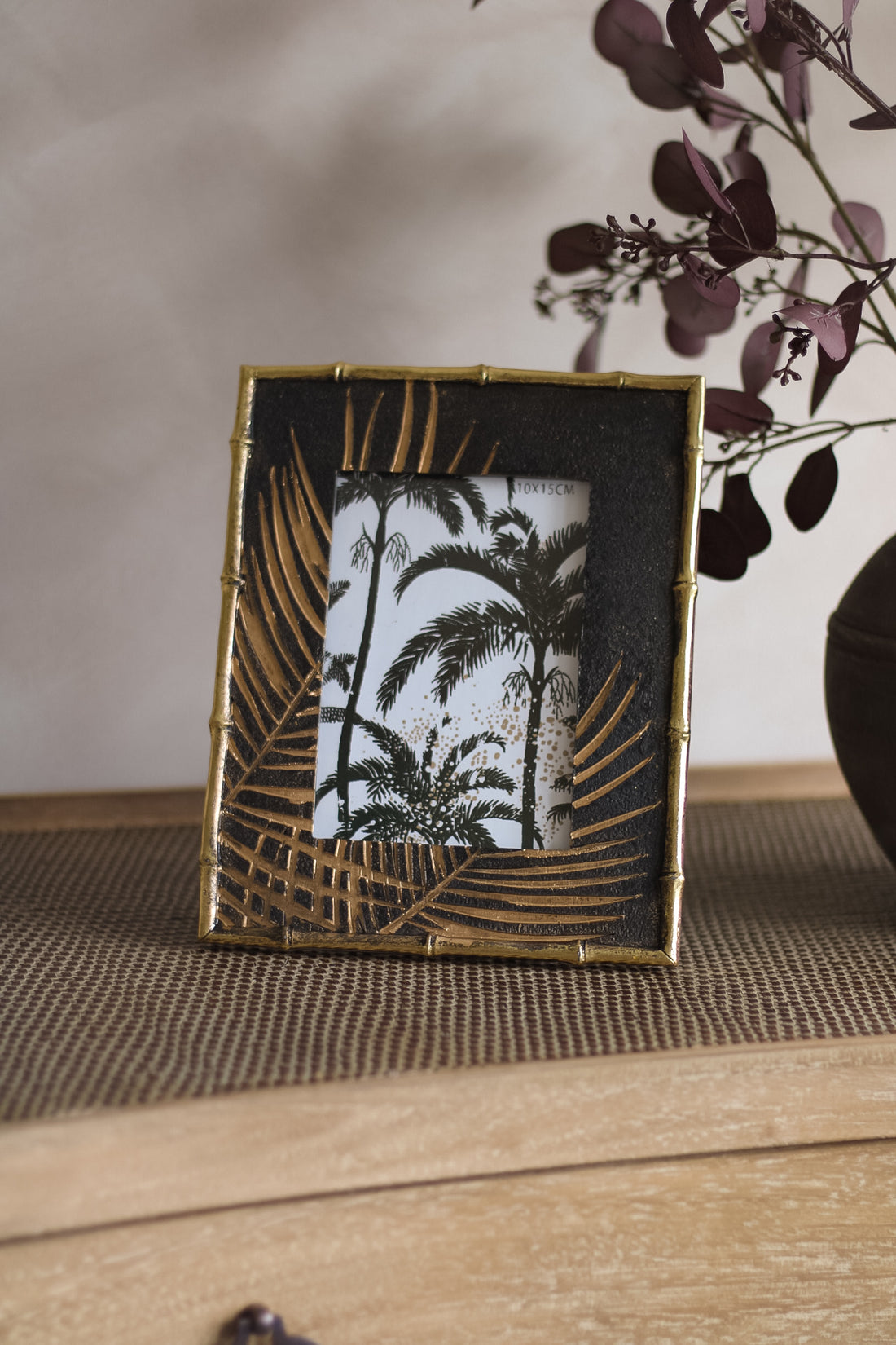 Decorative photo frame with leaf design on a wooden surface