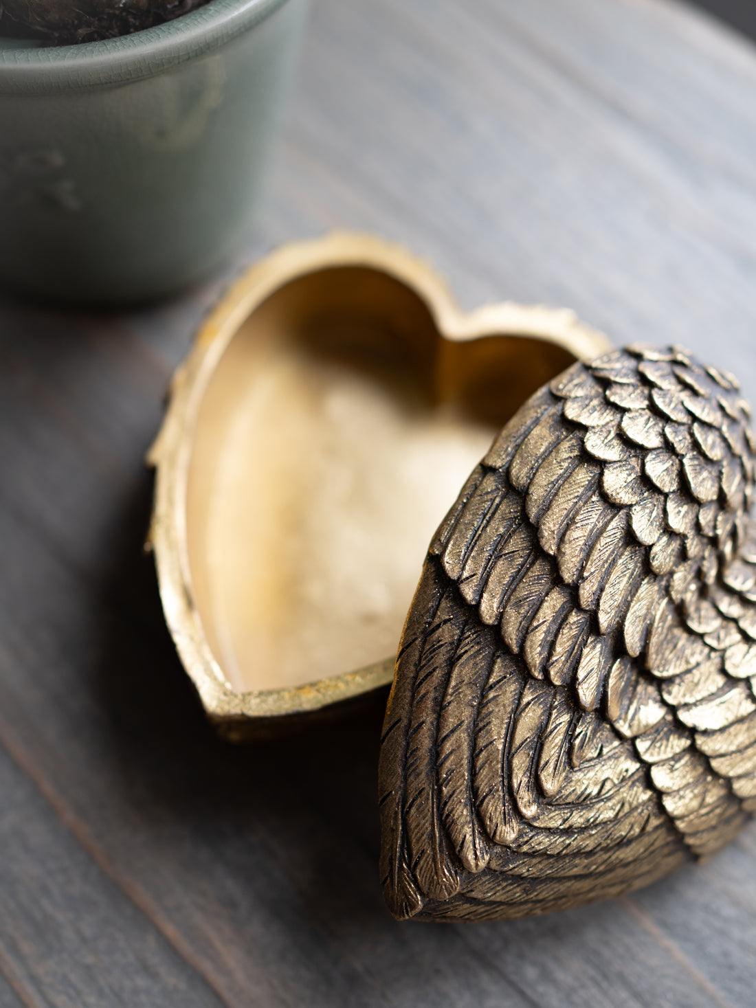 Bronze heart-shaped box with intricate design on a wooden surface