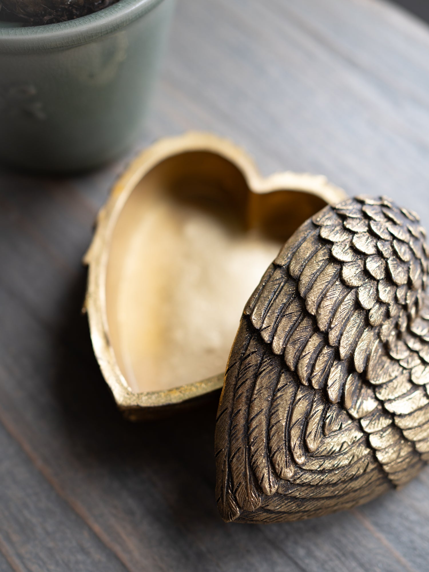 Bronze heart-shaped box with intricate design on a wooden surface