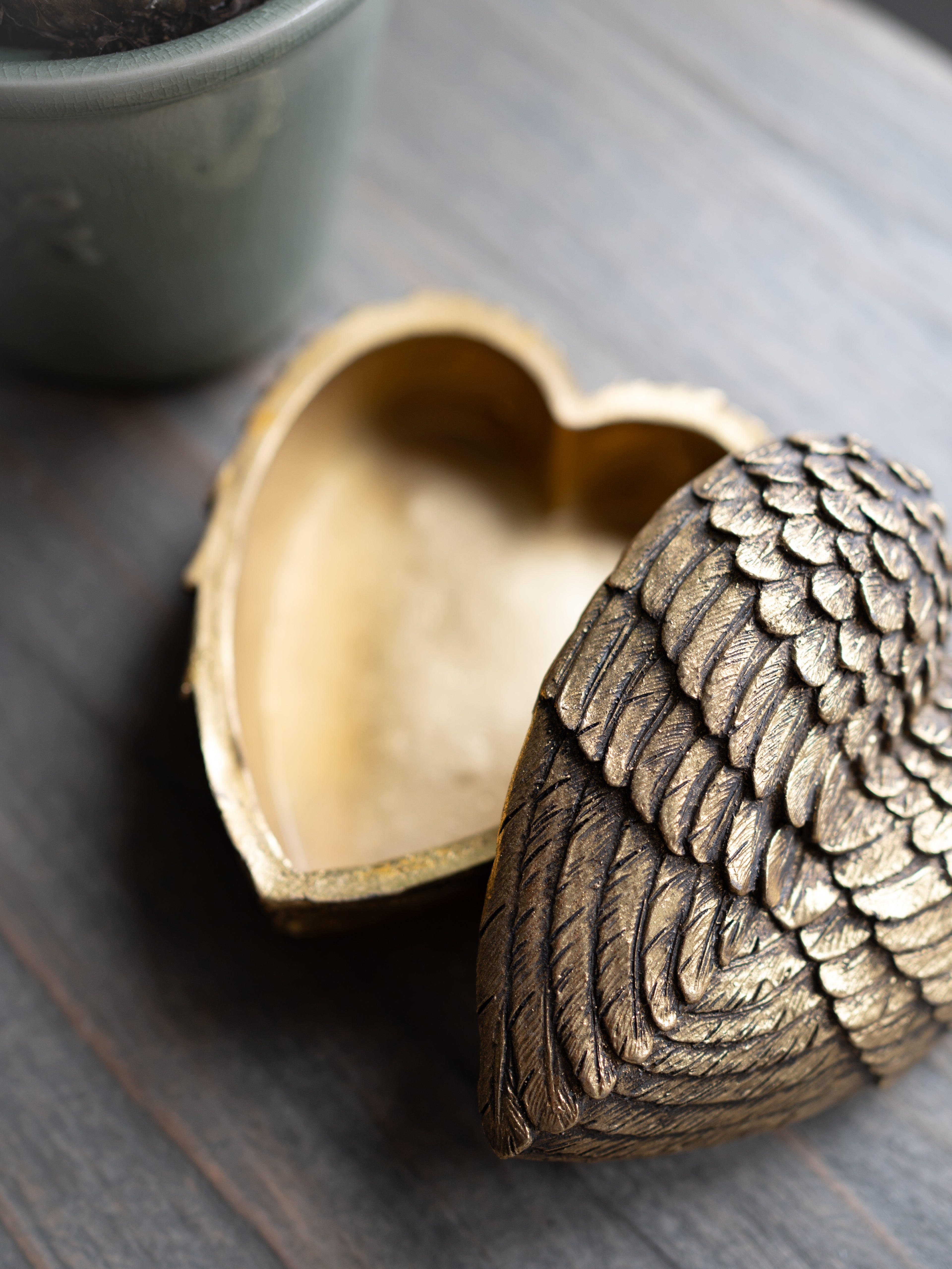 Bronze heart-shaped box with intricate design on a wooden surface