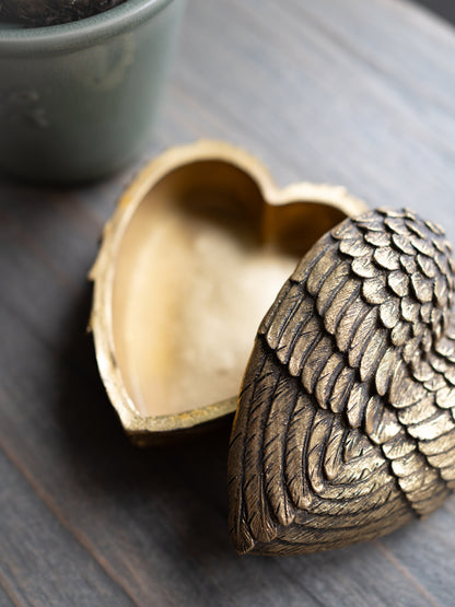 Bronze heart-shaped box with intricate design on a wooden surface